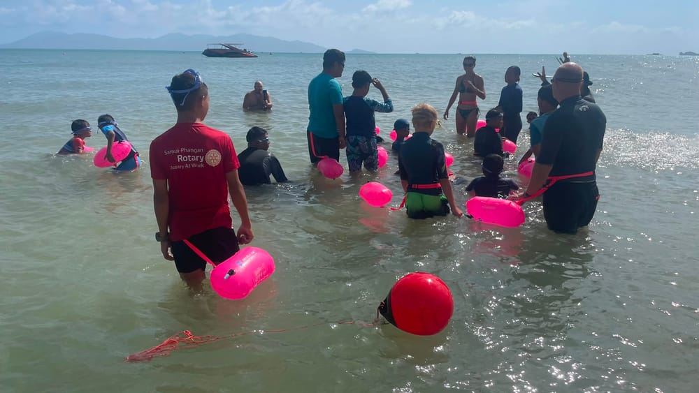 SLSC Koh Samui coach and Rotary volunteer training children in the ocean with rescue floats